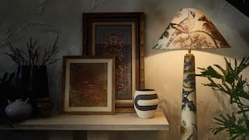 Een plank met een lijst, een vaas en een lamp.