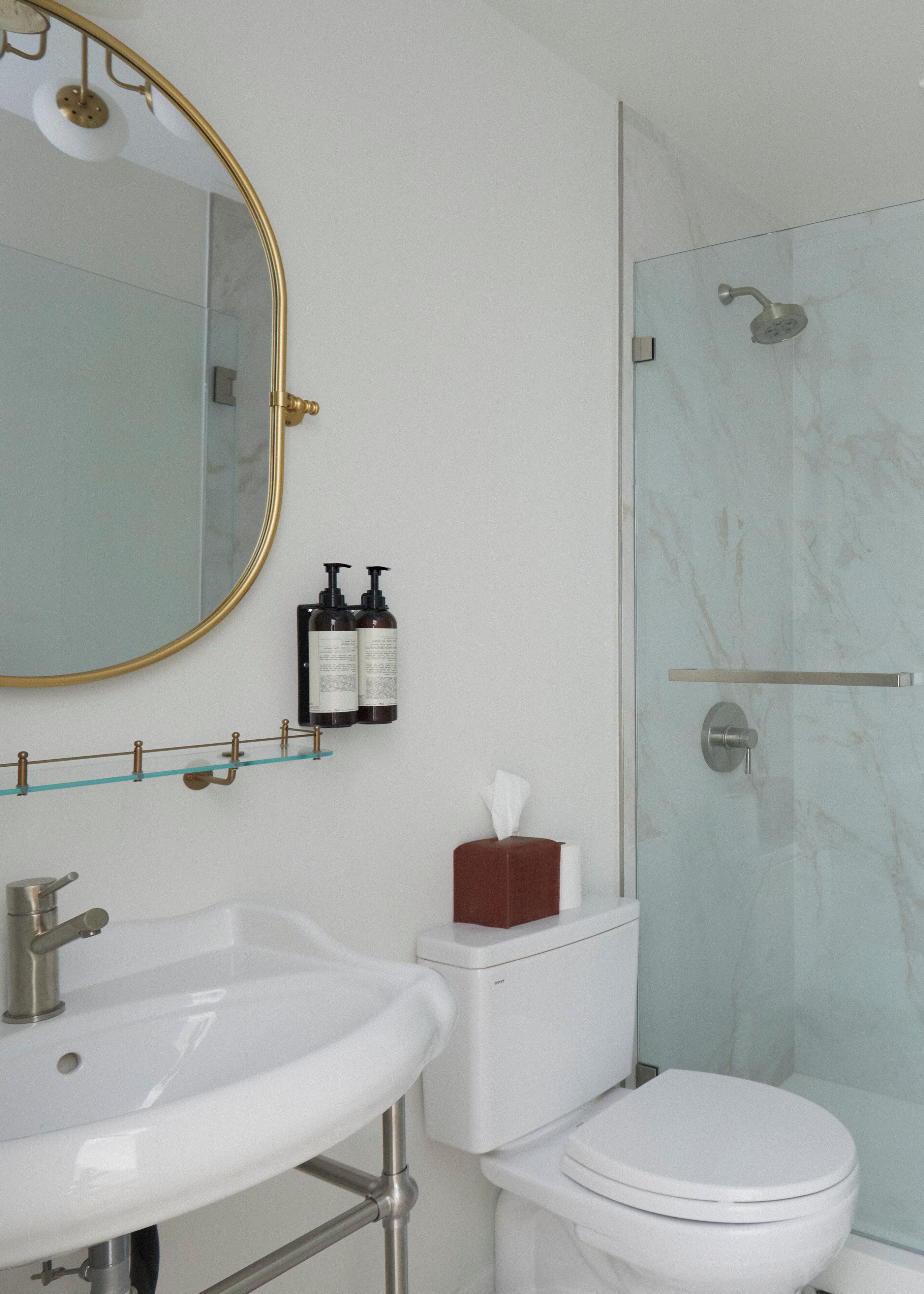 A bathroom with a white sink, a toilet, and a glass shower enclosure.