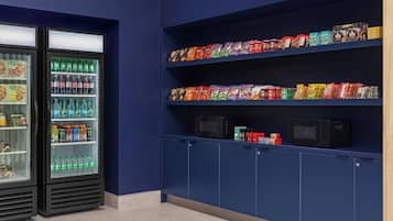 Een automatenruimte met snacks en drankjes, inclusief magnetrons en een koelkast.