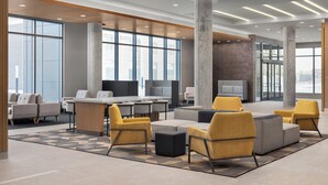A modern lounge area with seating, a reception desk, and large windows offering city views. - Holiday Inn Express Montreal Airport - St-Laurent by IHG (Montreal)