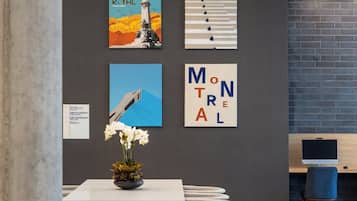 Un área de recepción con un mostrador, un jarrón de flores y cuatro obras de arte enmarcadas en la pared.