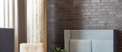 A modern living room with a grey sofa, a beige armchair, and a potted plant.