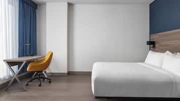 A hotel room with a bed, a desk, and a chair.