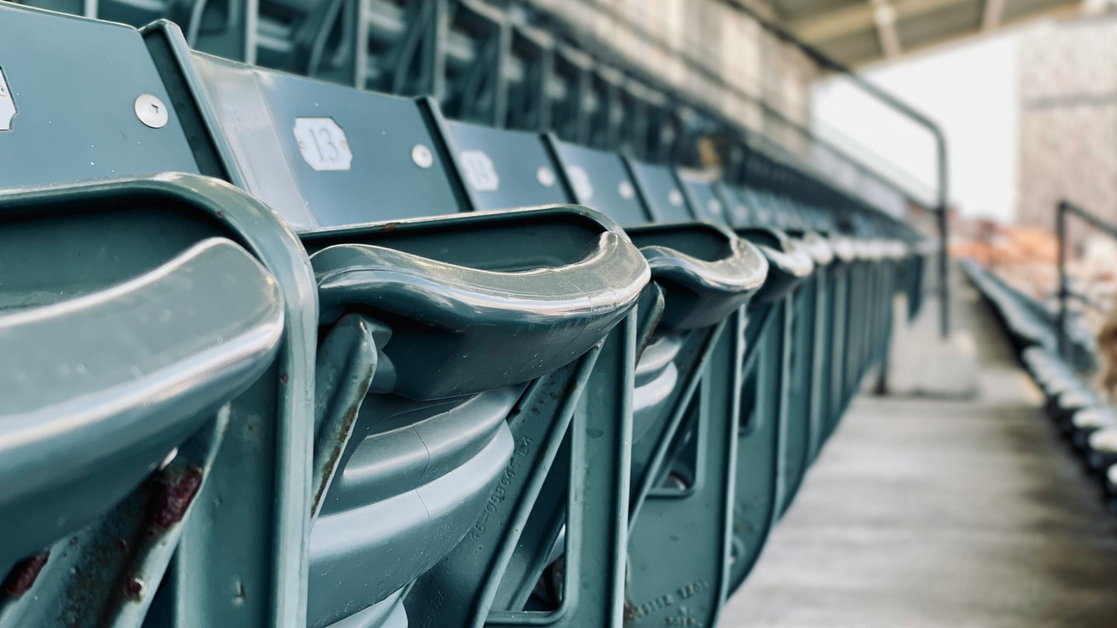 Rows of green stadium seats with visible seat numbers and a concrete floor.