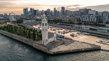 Une zone riveraine avec un imposant beffroi, un port de plaisance rempli de bateaux et, en arrière-plan, le profil de la ville.