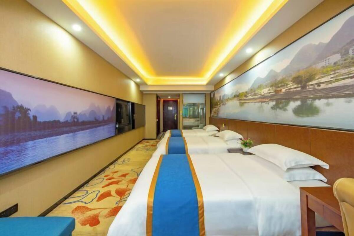 A hotel room with a large bed, a desk, and a wall-mounted TV.