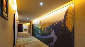 A hallway with a carpeted floor and a large mural depicting a mountainous landscape. - Manhattan Hotel Guilin Liangjiang Sihu Arctic Plaza (Guilin)