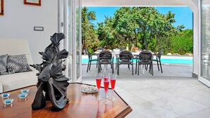 Un interior moderno con vistas a una piscina exterior y abundante vegetación.
