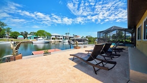 A waterfront patio with lounge chairs, a pool, and boats docked nearby. - 3-BR/2 Bath waterfront home with direct access to Gulf. Pool, kayaks and dock (Hernando Beach)