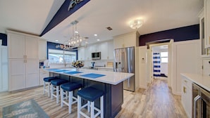 A modern kitchen with a central island, bar stools, a chandelier, and a view to the outside. - 3-BR/2 Bath waterfront home with direct access to Gulf. Pool, kayaks and dock (Hernando Beach)