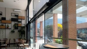 Ein modernes Café mit großen Fenstern, Holzstühlen und einem Fliesenboden.