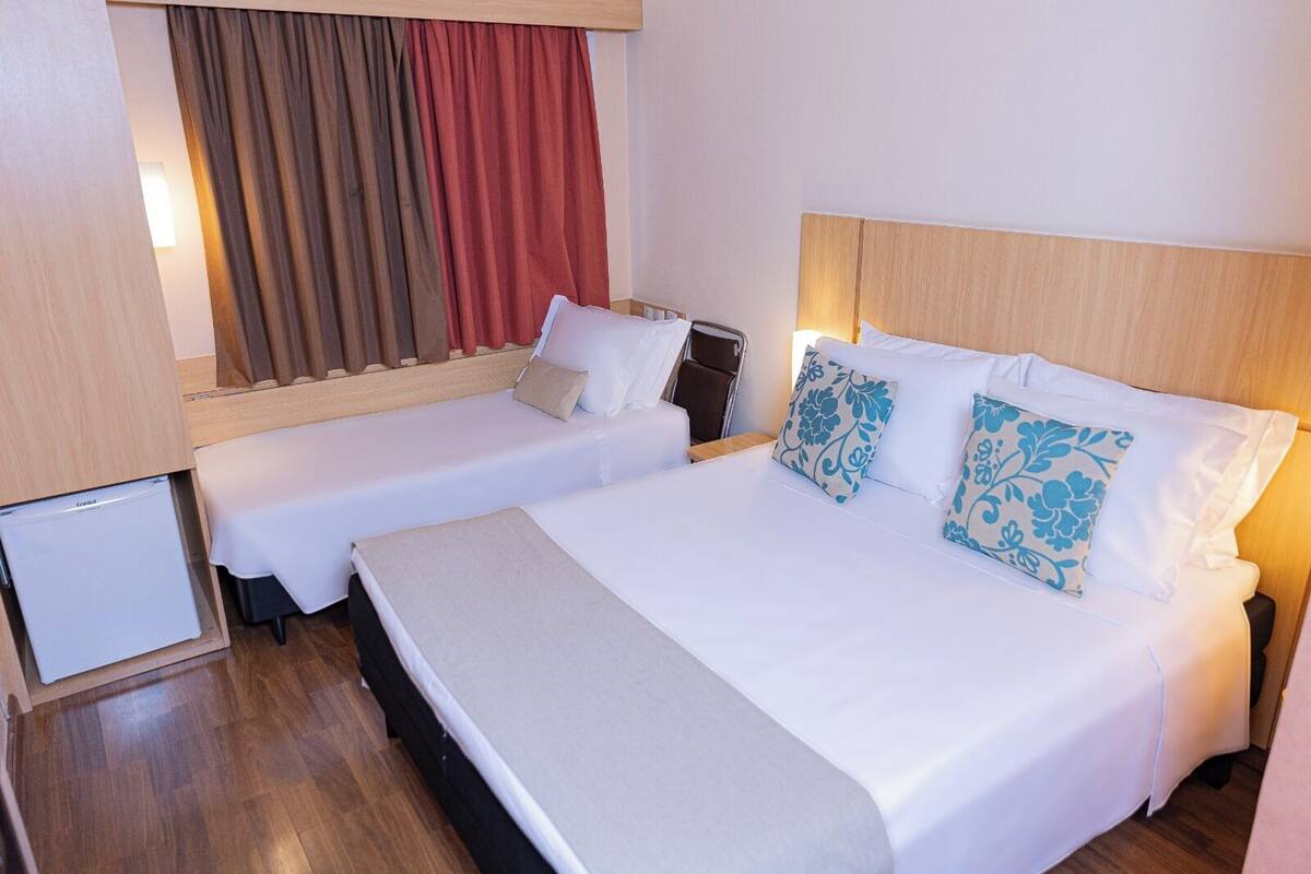 Ein Hotelzimmer mit zwei Einzelbetten, einem kleinen Kühlschrank und einem Holzkopfteil.