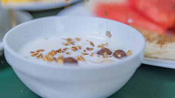 A bowl of yogurt with granola and a spoon on a green placemat.