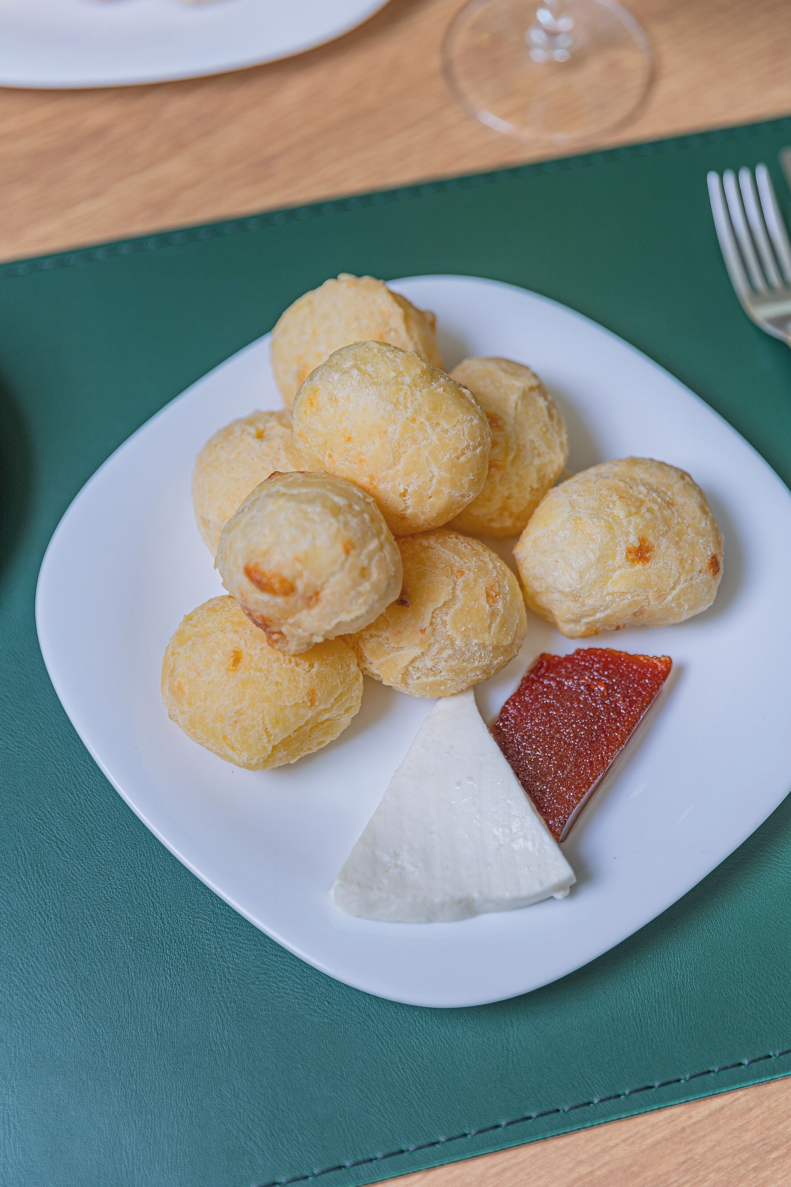 Un piatto di bocconcini di formaggio e una fetta di formaggio su un sottopiatti verde.
