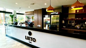 Ein Hotel-Rezeptionsbereich mit einer Theke, einem Schild mit der Aufschrift 'LIETO HOTEL' und einem mit Getränken gefüllten Kühlschrank.