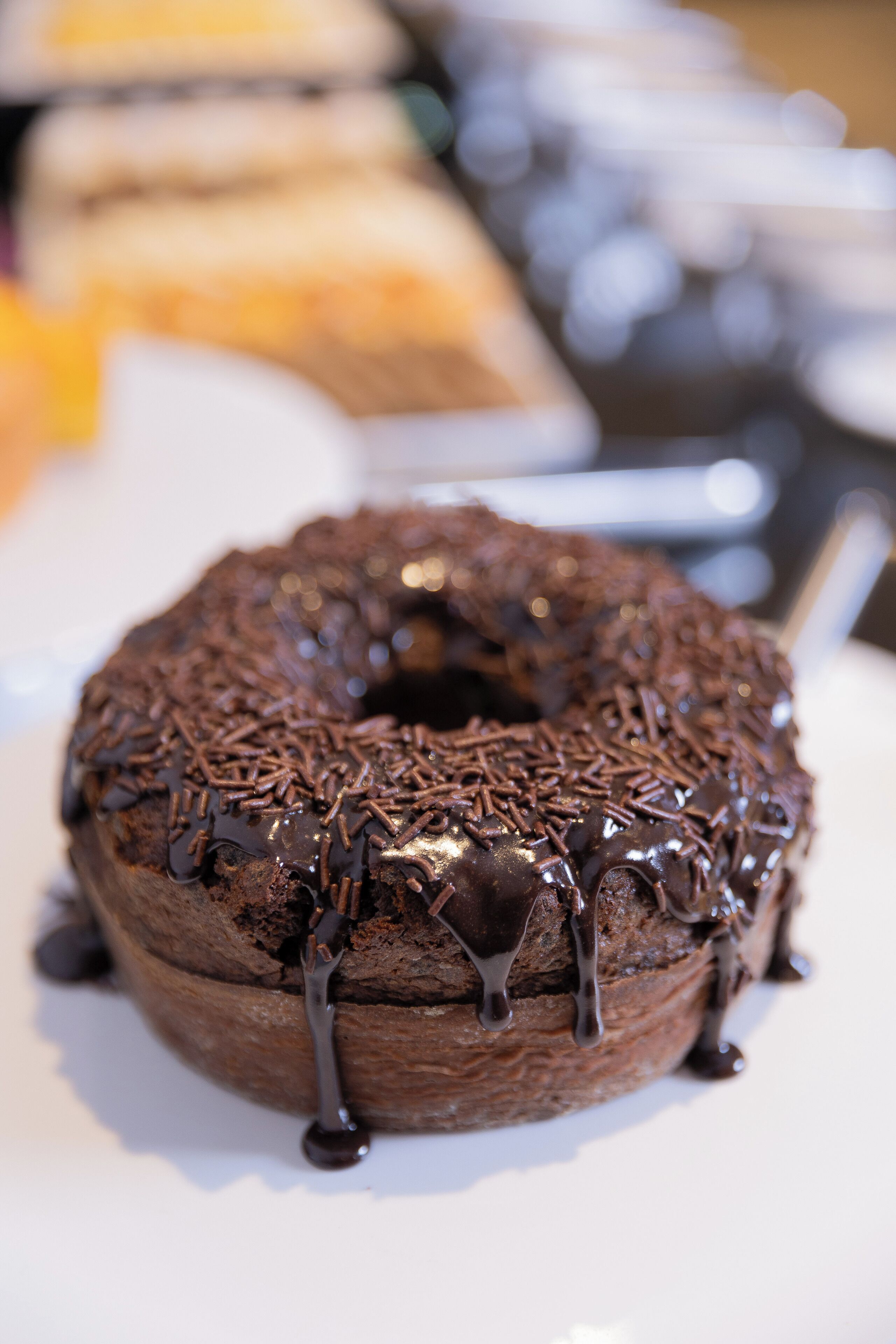 Un beignet au chocolat, parsemé de vermicelles au chocolat et recouvert d’un glaçage au chocolat qui en dégouline.