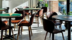 Ein modernes Café-Interieur mit Tischen, Stühlen und einer Treppe mit schwarzen Geländern.