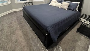 A bedroom with a bed, ceiling fan, artwork, and windows. - Comfort Zone (Wilmington)