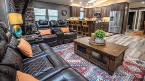 Ein modernes Wohnzimmer mit Ledersofas, einem Couchtisch und einem gemusterten Teppich.