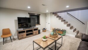 Ein Wohnzimmer mit Fernseher, Unterhaltungseinheit, Couchtisch und einer Treppe.