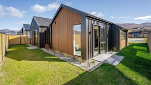 Een modern huis met een grote glazen deur, een houten gevel en een verzorgd gazon.