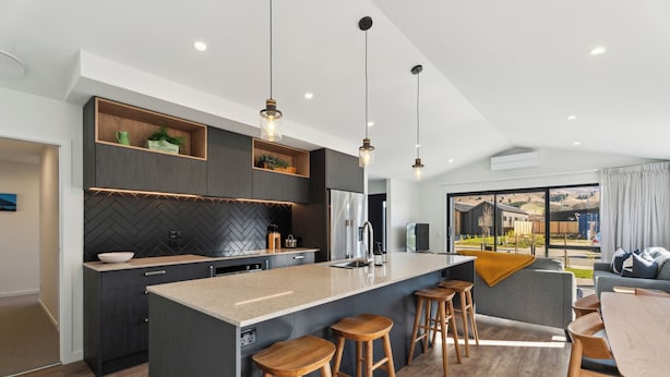 Een moderne keuken met een groot keukenblok, houten krukken en hanglampen.