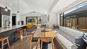 Een moderne keuken met een centraal eiland, houten krukken en een groot raam met uitzicht op de omgeving.