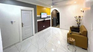 A modern living room with a sofa, a coffee table, and a TV. - Nice apartment with AC in Greater Accra Region (Greater Accra Region)