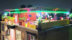 A rooftop terrace with a wooden structure, potted plants, and colorful lighting. - Nice apartment with AC in Greater Accra Region (Greater Accra Region)