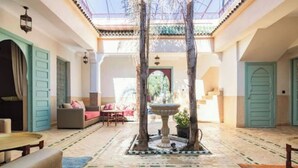 A spacious indoor courtyard with a fountain, seating areas, and a view through a glass ceiling. - Riad salix d'agafay (Marrakech)