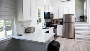 Una cocina moderna con armarios blancos, electrodomésticos de acero inoxidable y un amplio ventanal que proporciona luz natural.