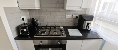 A compact kitchen with a gas stove, a toaster, and a coffee maker.