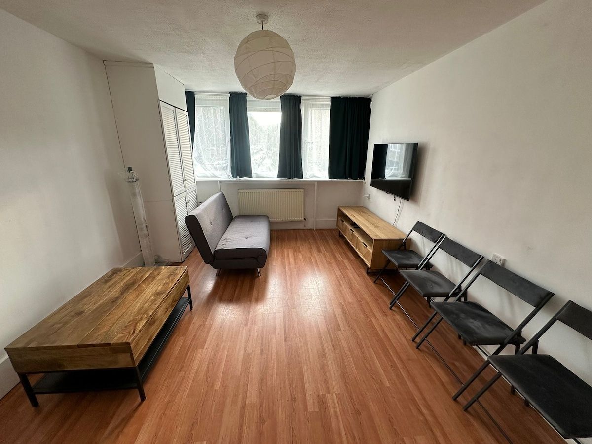 A room with a sofa, a wooden bench, and a row of chairs.
