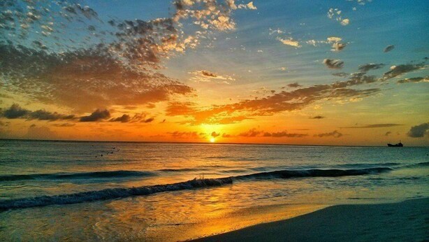 A sunset over a beach with waves and a boat in the distance. - Vida Mejor--Poolside (Private Pool) (Holetown)