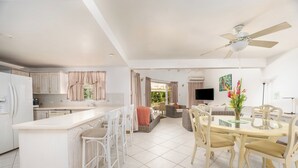 A spacious kitchen with a central island, white cabinetry, and a dining area with a glass-top table and chairs. - Vida Mejor--Poolside (Private Pool) (Holetown)