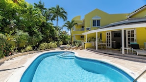 A swimming pool with a clear blue water, surrounded by a patio area with chairs and a table. - Vida Mejor--Poolside (Private Pool) (Holetown)