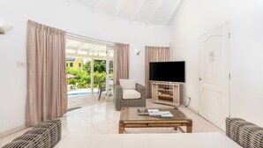 A spacious living room with a flat-screen TV, wicker furniture, and a glass coffee table. - Vida Mejor West Pool (Private Pool) (Holetown)