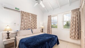 A bedroom with a bed, two bedside tables with lamps, a ceiling fan, and a window with curtains. - Vida Mejor West Pool (Private Pool) (Holetown)