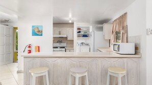 A modern kitchen with a central island, white cabinetry, and a microwave. - Vida Mejor--Waterfall (Private Pool) (Holetown)