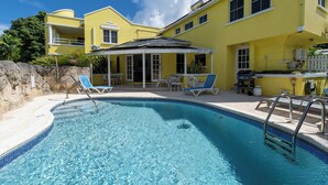 A swimming pool with lounge chairs and a covered patio area. - Vida Mejor--Waterfall (Private Pool) (Holetown)