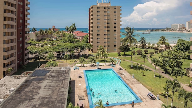 A rooftop pool with a view of the ocean and palm trees. - Emerald One Bedroom Suite (Ocho Rios)