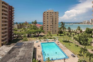 A rooftop pool with a view of the ocean and palm trees. - Emerald One Bedroom Suite (Ocho Rios)