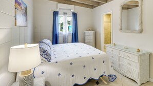 A bedroom with a bed, a dresser, a mirror, and a ceiling fan. - Waterfront Colony Beach Duplex! w/ Golf Cart! (Key Colony Beach)