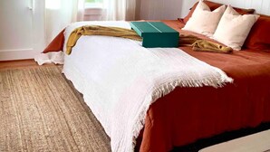 A bedroom with a bed, a window with curtains, a wooden ceiling, and a white wall. - 3-bedroom 2 bath cottage-Walk to beach or golf
Course.Hot Tub and outside shower (Kitty Hawk)