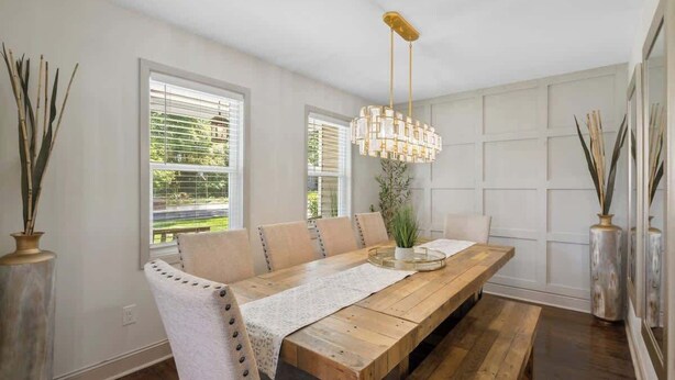 Un espace repas avec une table en bois, des bancs et un luminaire suspendu.