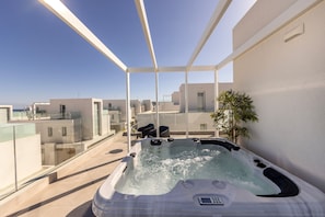 A hot tub on a balcony with a clear view of the surrounding buildings.