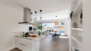 A modern kitchen with white cabinetry, a central island, and pendant lighting.