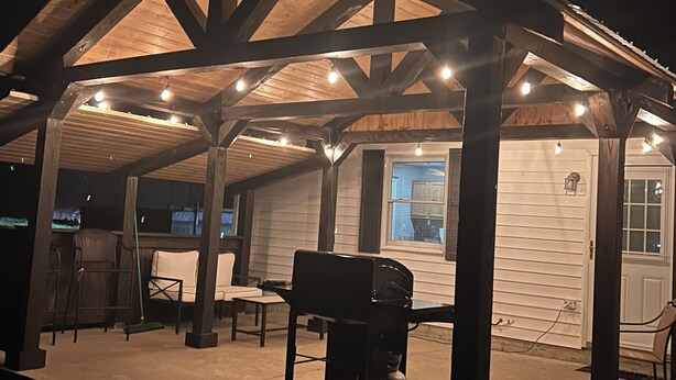 A covered outdoor patio with a grill and seating area.