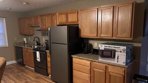 A kitchen with wooden cabinets, a stainless steel refrigerator, a microwave, and a dishwasher.