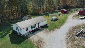 A white mobile home with a metal roof, a small attached garage, and a fenced yard.